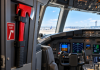 Red emergency crash axe mounted inside a modern airliner cockpit beside the flight controls.