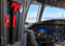 Red emergency crash axe mounted inside a modern airliner cockpit beside the flight controls.